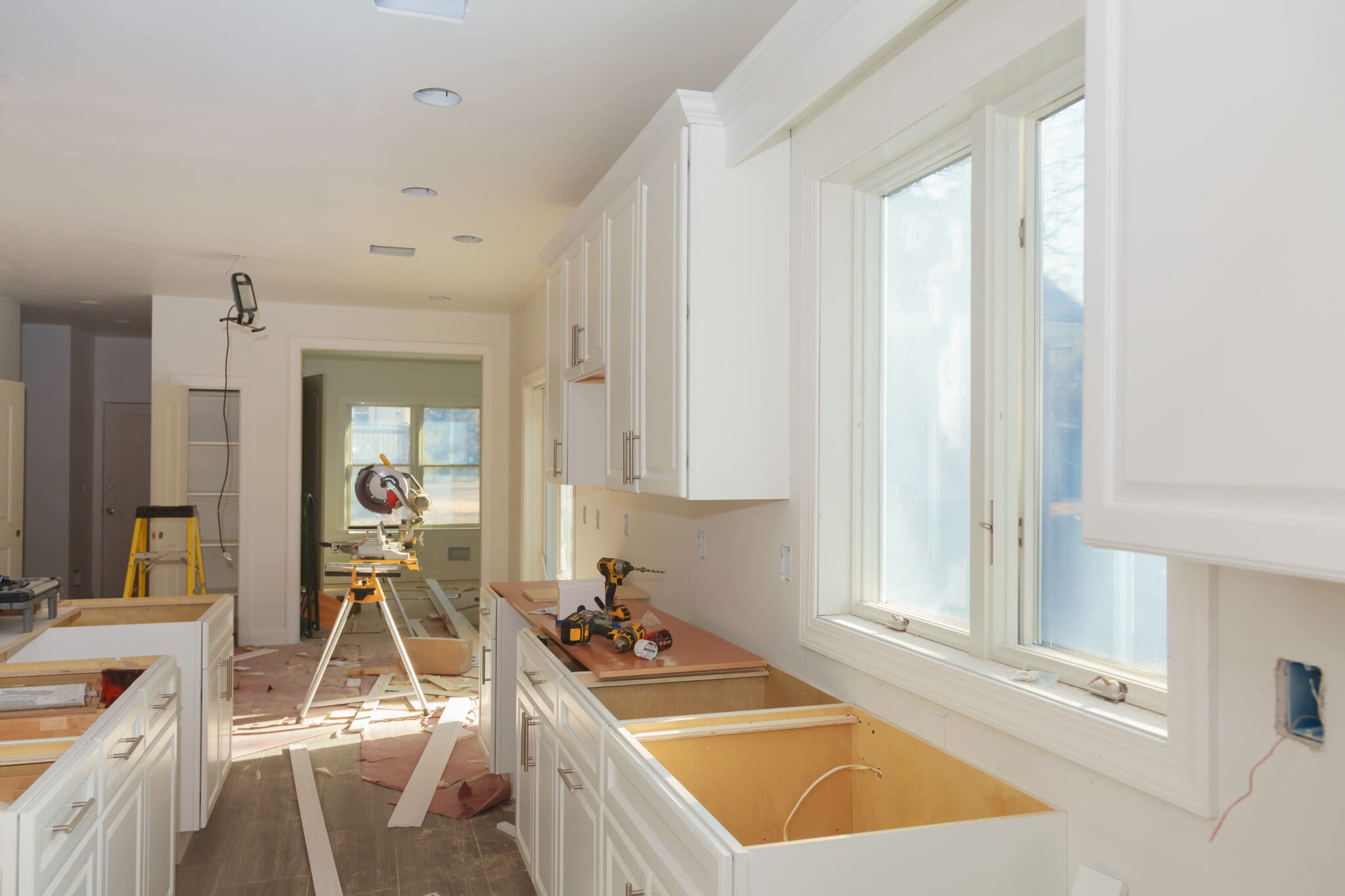 Kitchen renovation with white cabinets and saw